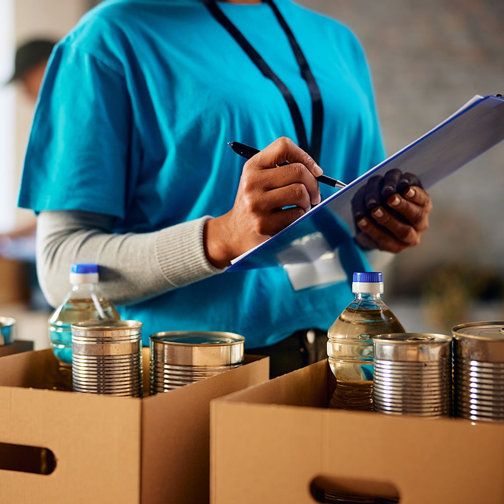 Volunteer writing on a clipboard near boxes of donated food