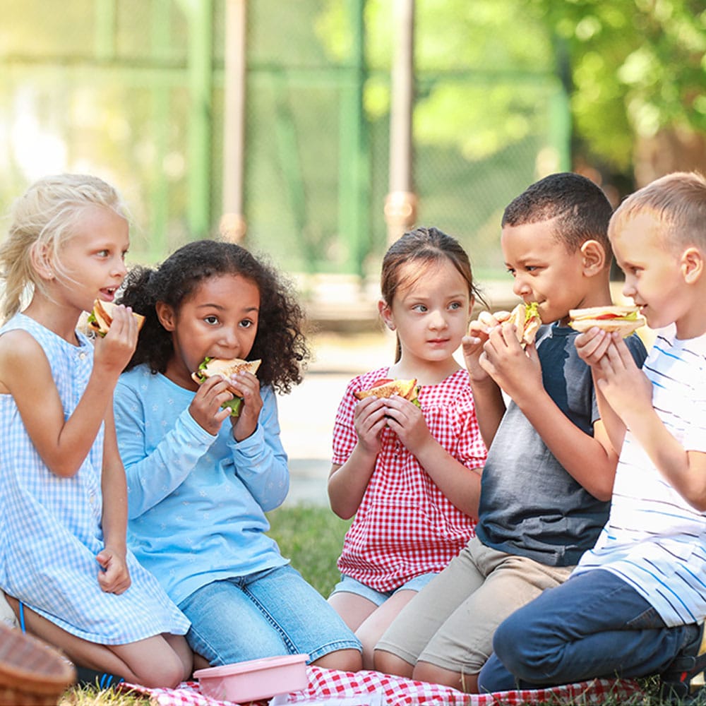 Children eating sandwiches outdoors
